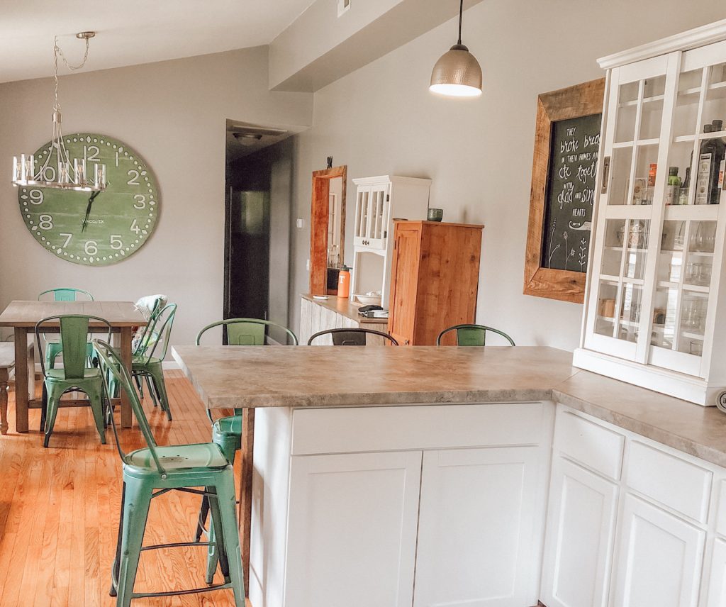 clean and bright kitchen and dining area with teal chairs and white cabinets