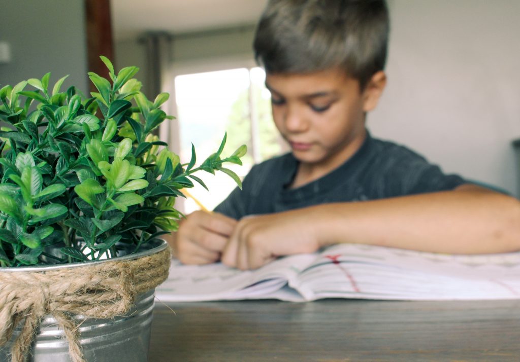 boy writing in math book at dining room table