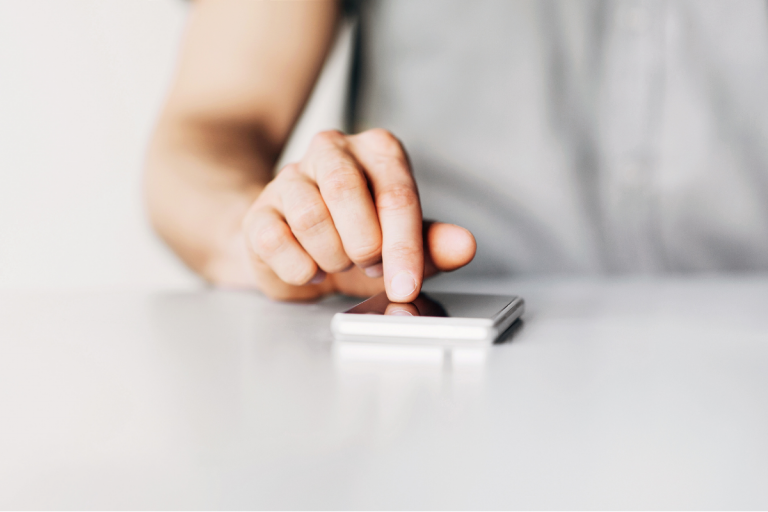 woman tapping phone screen on table