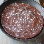 sourdough brownies in cast iron skillet topped with powdered sugar