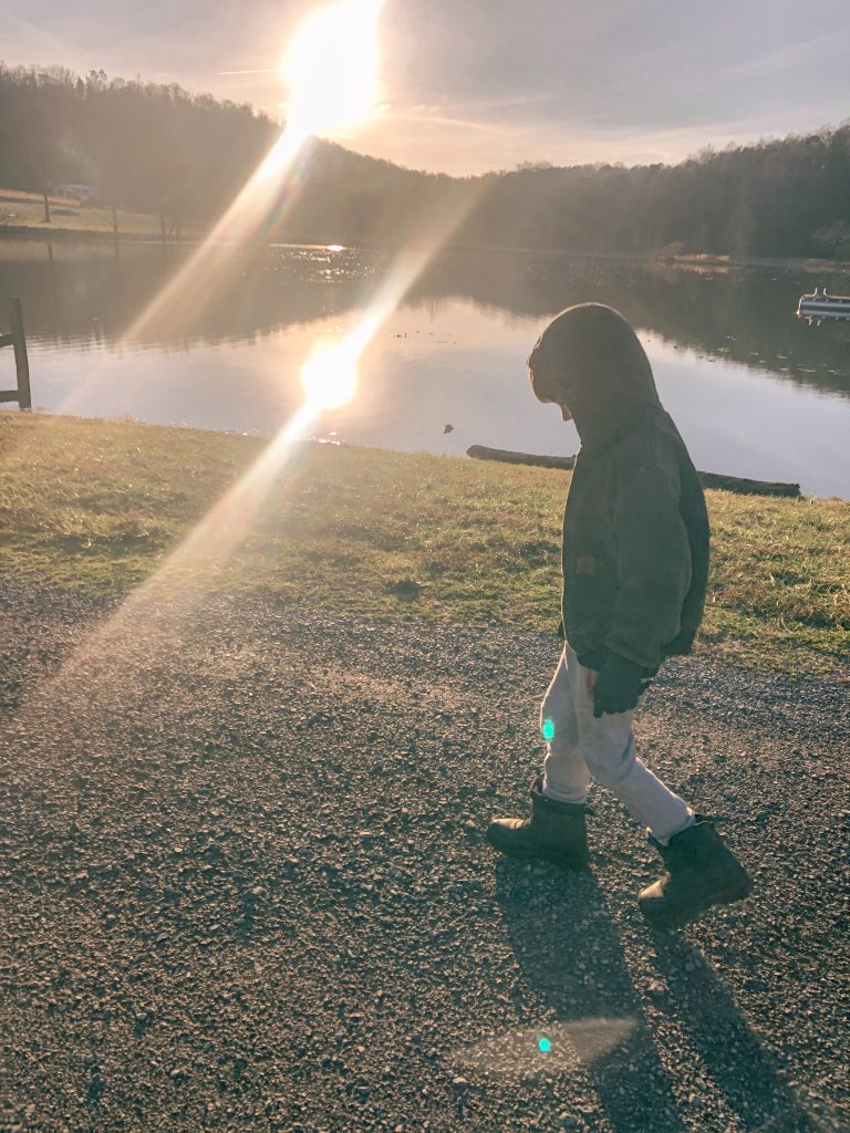 4 year old boy walking on gravel by a lake