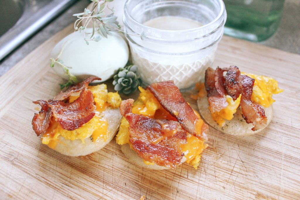 mini breakfast pizzas arranged on wood board with flowers and cream