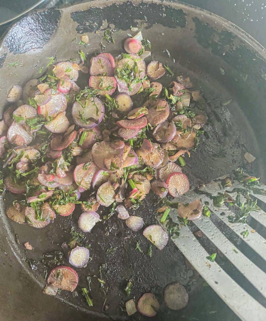 thinly cut radish cooked in cast iron skillet with spatula