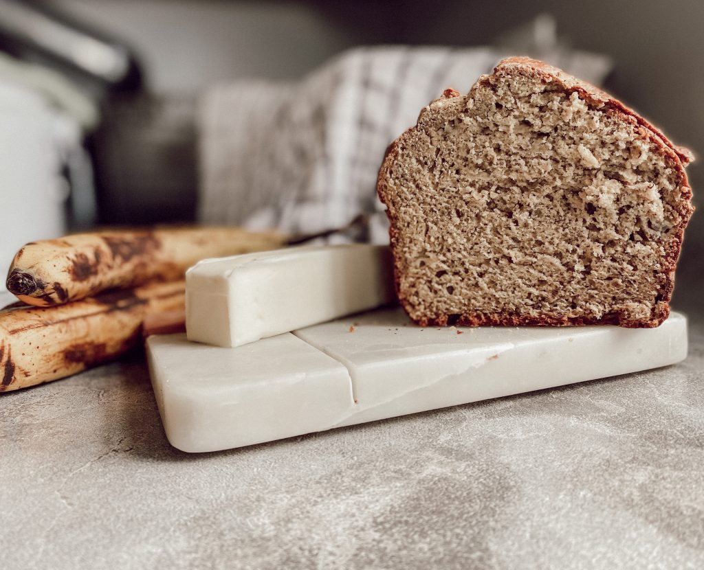 inside of sourdough banana bread loaf with butter and ripe bananas in background