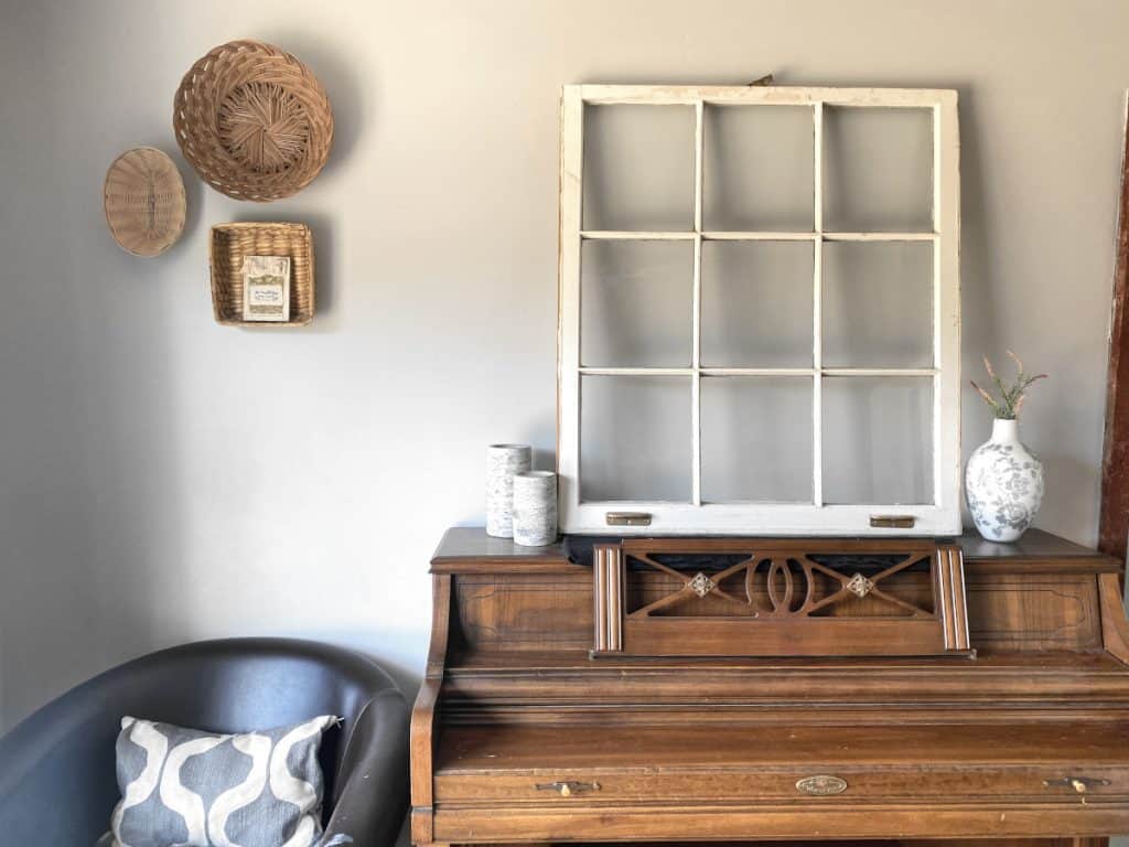 upright piano with simple rustic decor and baskets hanging on wall