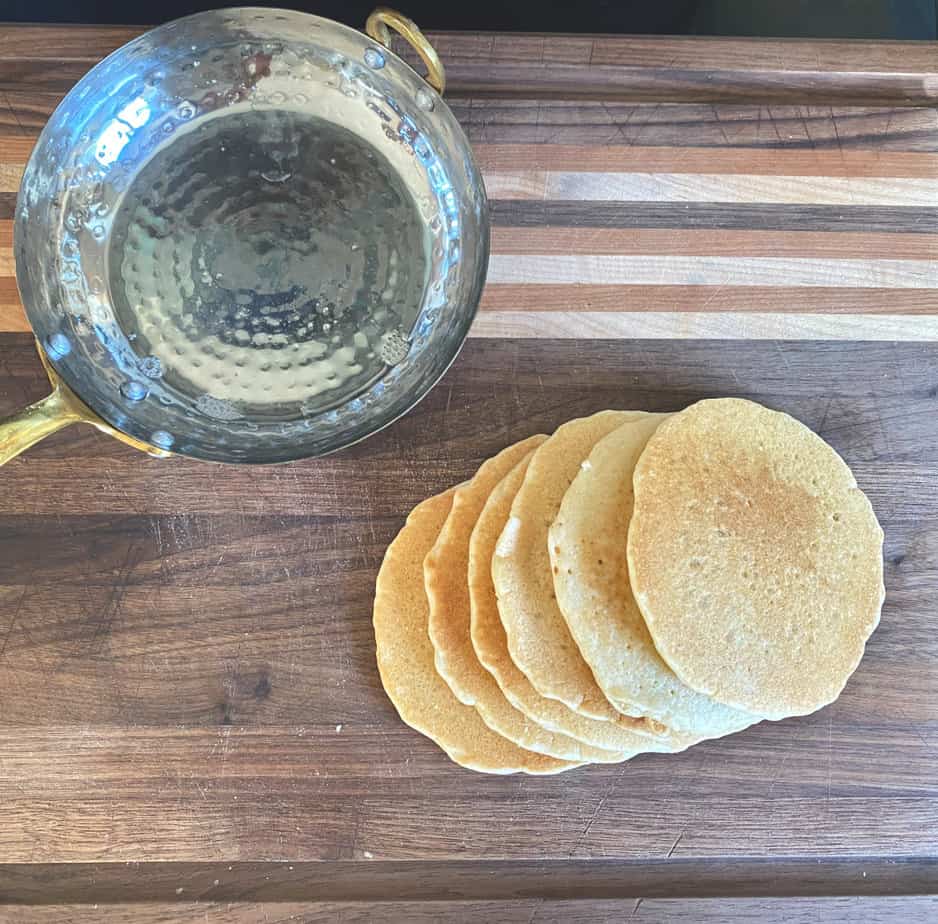 sourdough pancakes on handmade cutting board with copper pan