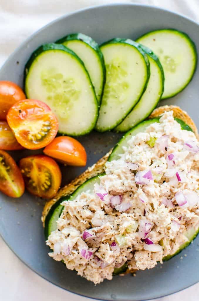 light tuna salad served on toast with cucumbers and tomatoes