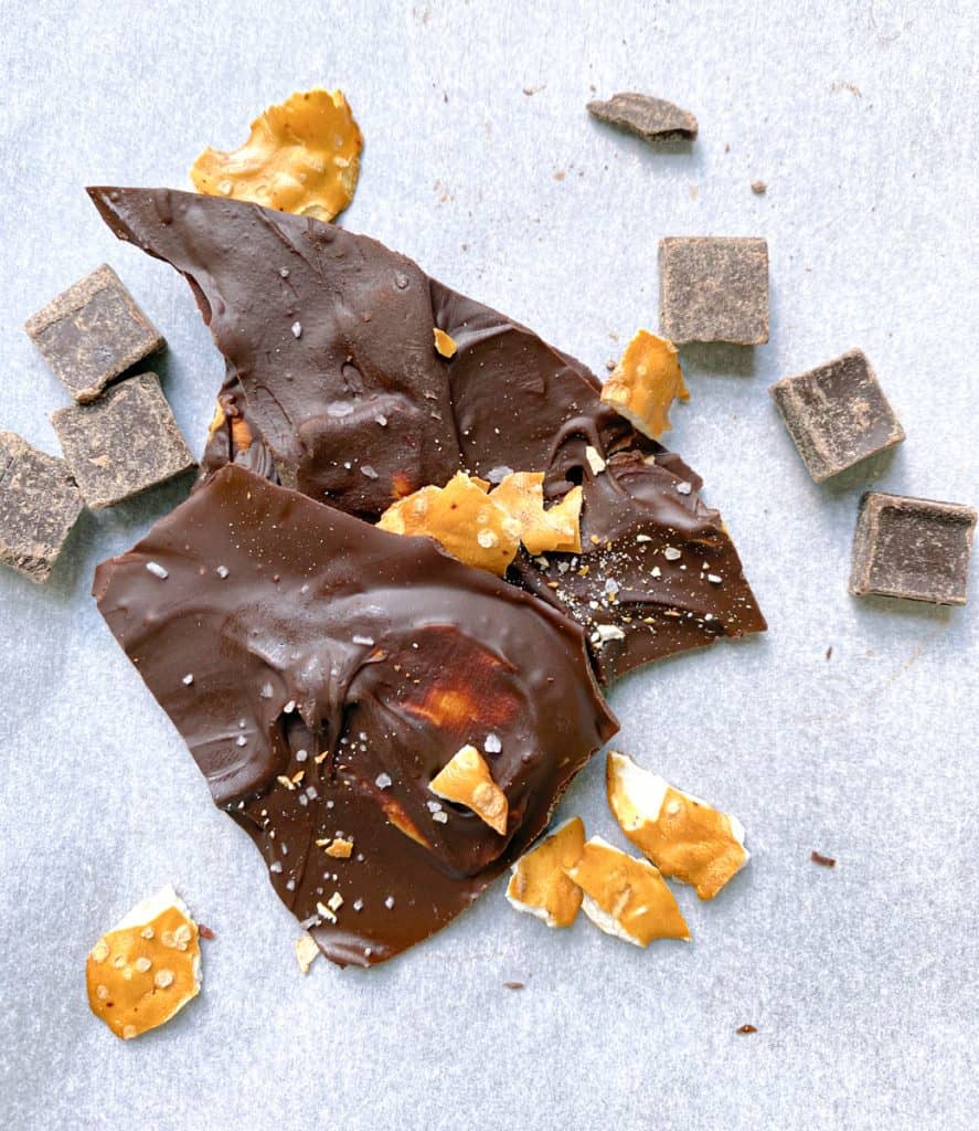 dark chocolate pretzel bark topped with crushed pretzels and surrounded by chocolate chunks