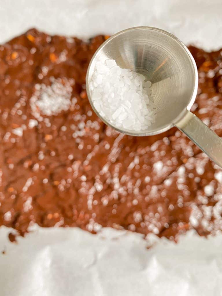 kosher salt in metal spoon with chocolate bark in background