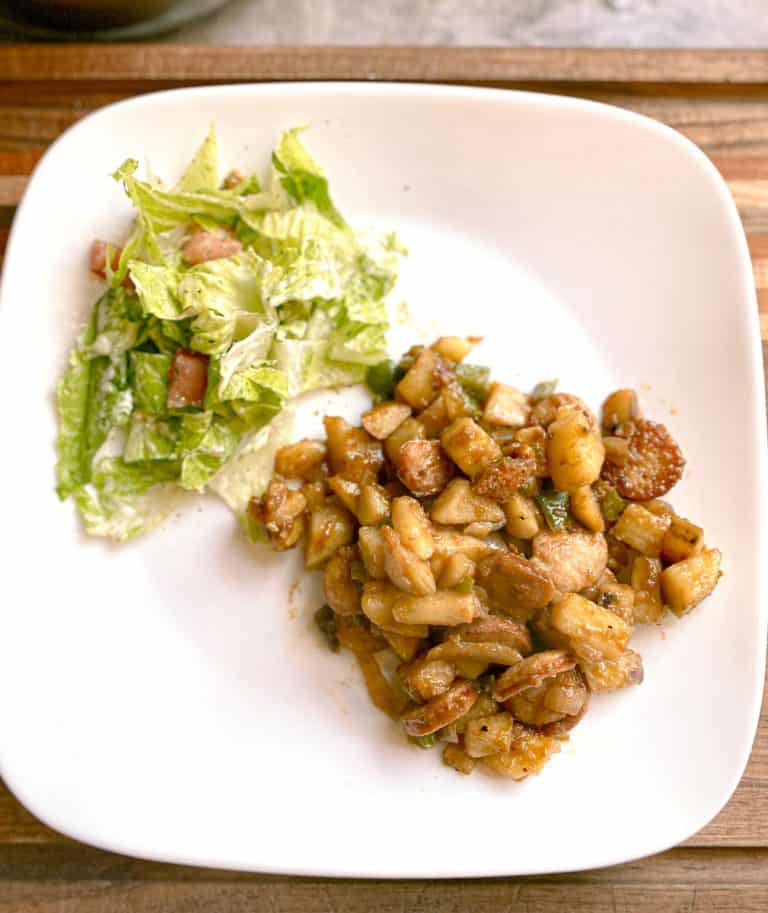 smothered potatoes and sausage with side salad on white plate