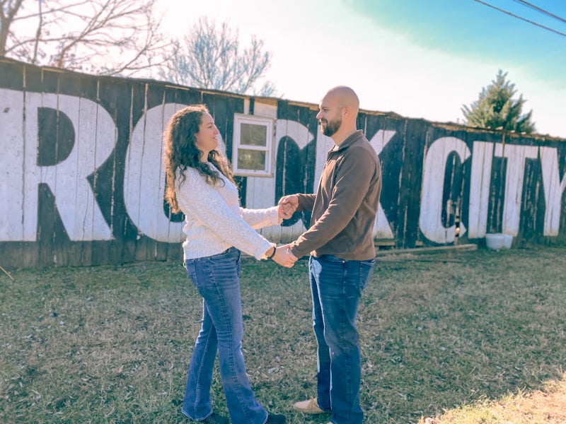 homesteading couple in front of barn