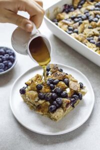 syrup being poured on blueberry french toast casserole