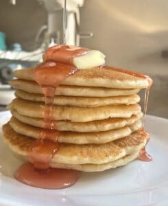 peach syrup poured on sourdough pancakes with butter
